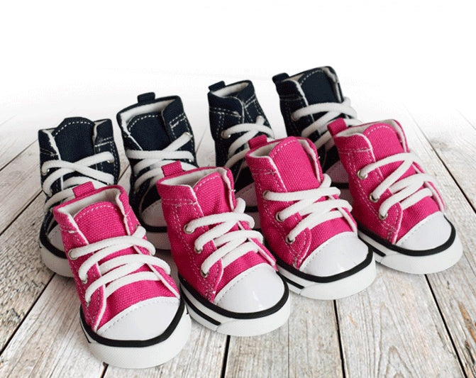 Pair of pink high-top sneakers with white laces on a wooden surface. Bishop X 