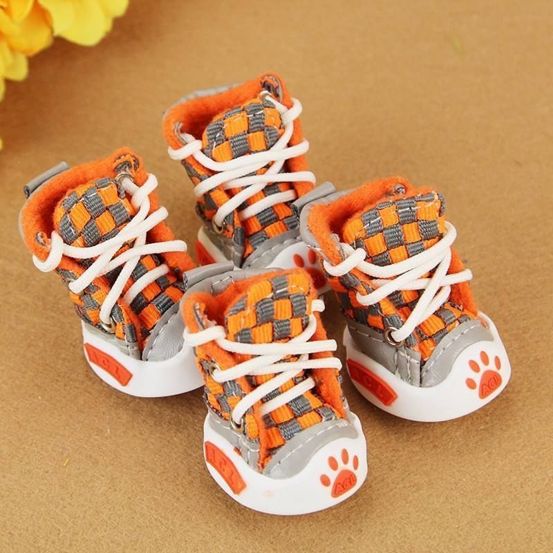 Orange and gray checkered pet boots with white laces on a brown background. Bishop X 