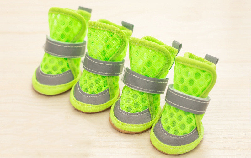 Four green pet boots with gray straps on a light beige background. Bishop X 