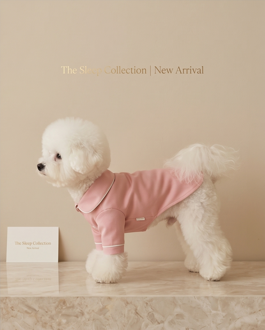 White dog wearing a pink outfit with 'The Sheep Collection' branding on a beige background. Bishop x 