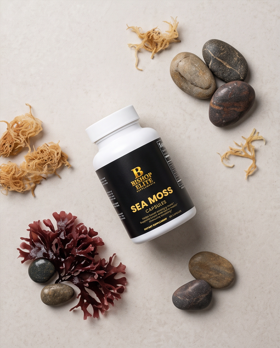 A bottle of Best of Beaches Sea Moss Capsules lies on a light beige textured surface, surrounded by natural sea moss, smooth river stones, and dried seaweed. Bishop Elite Supplements 