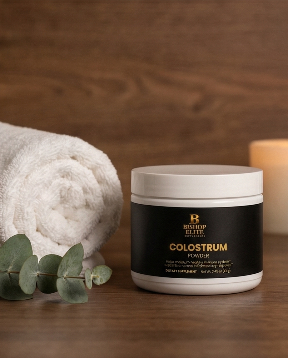 Jar of Bishop Elite Colostrum Powder on a wooden surface with a towel and eucalyptus leaves. Bishop Elite Supplements 