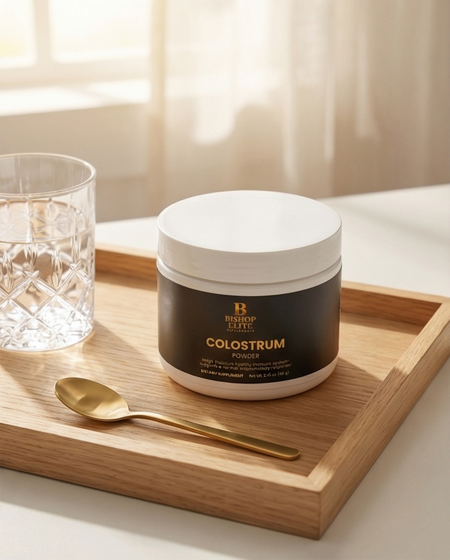 Jar of colostrum powder on a wooden tray with a glass and spoon in the background. Bishop Elite Supplements 