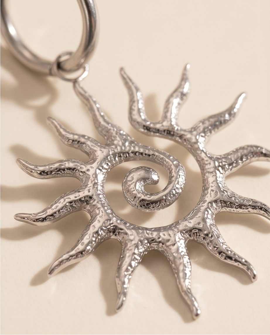 Silver sun-shaped keychain on a beige background.   BISHOP X 